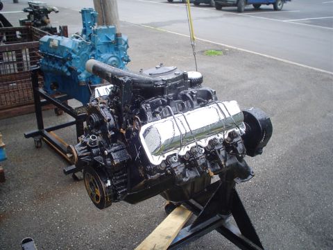 1981 Ford Bronco - Two engines are displayed on stands outdoors, with a parking lot and vehicles in the background.