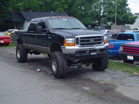 1981 Ford Bronco - This lifted black Ford F-250 Super Duty truck is shown from a 3q-front angle, with other vehicles visible in the background.