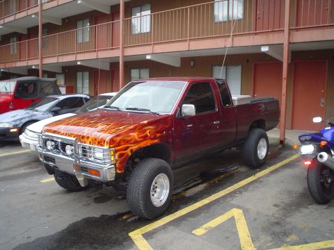 1981 Ford Bronco - Maroon pickup truck with flame decals parked next to other vehicles.
