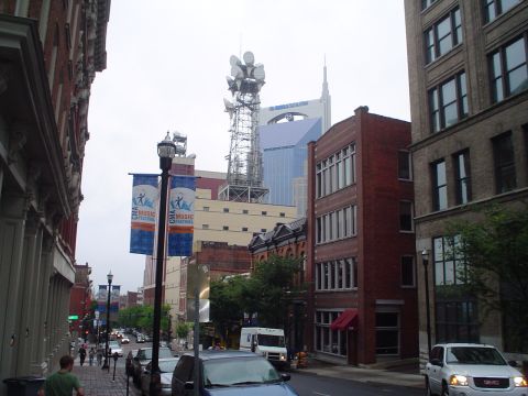 1981 Ford Bronco - A street scene in a city, CMA Music Festival banners and a prominent radio tower against a cloudy sky.