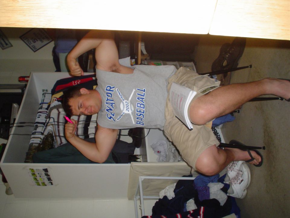 Man in a gray t-shirt with 'Senator Baseball 2002' text, holding a pink pen