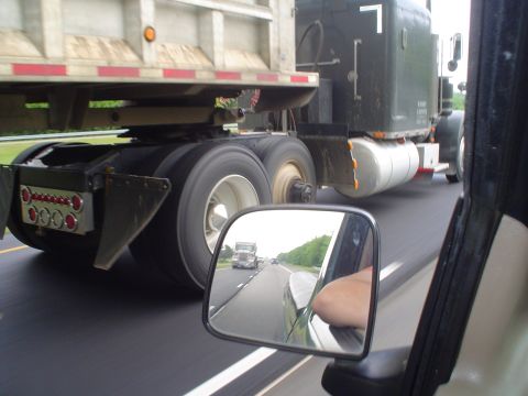 1981 Ford Bronco - Driving on highway behind a semi-truck, with another semi visible in the side mirror.