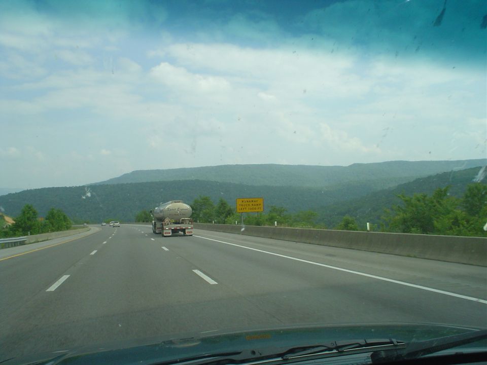 Highway driving with a tanker truck ahead and mountains in the background