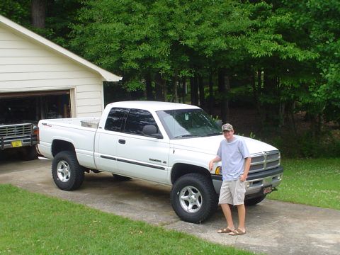 1981 Ford Bronco - A white pickup truck is parked in a driveway next to a garage, with a person standing beside it.