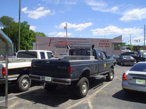 1981 Ford Bronco - Ford pickup truck with dual exhaust stacks and a toolbox in the bed is parked in a lot.