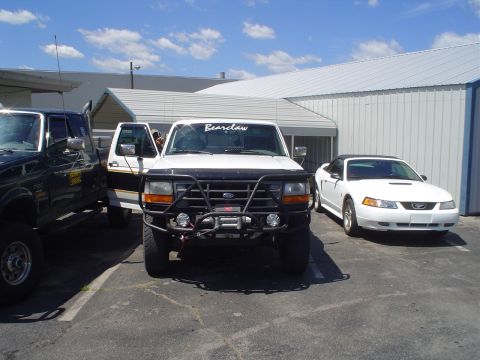 1981 Ford Bronco - Three vehicles are parked outside a building on a sunny day.