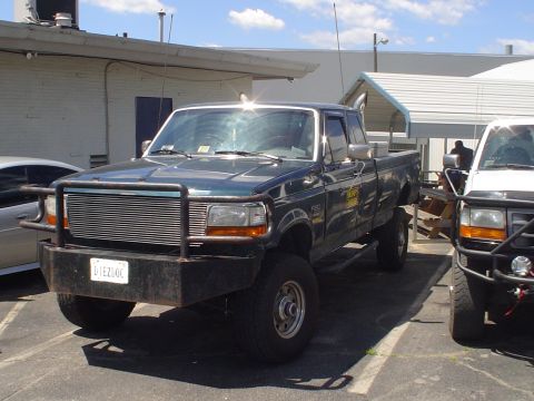 1981 Ford Bronco - This dark green pickup truck features a prominent aftermarket bumper and chrome grille. The license plate is visible.