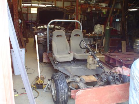 1981 Ford Bronco - This custom vehicle chassis is in a workshop, undergoing modifications with its hood open.
