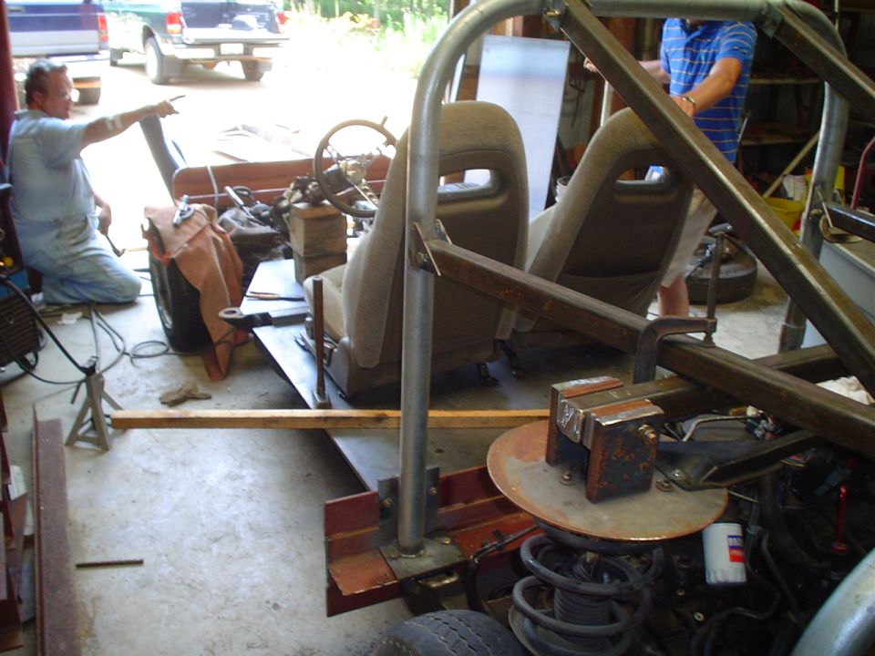 Custom off-road vehicle build in progress with roll cage, bucket seats, and steering wheel visible