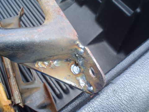 1981 Ford Bronco - Close-up of a heavily welded metal bracket, showing signs of rust and repair work.