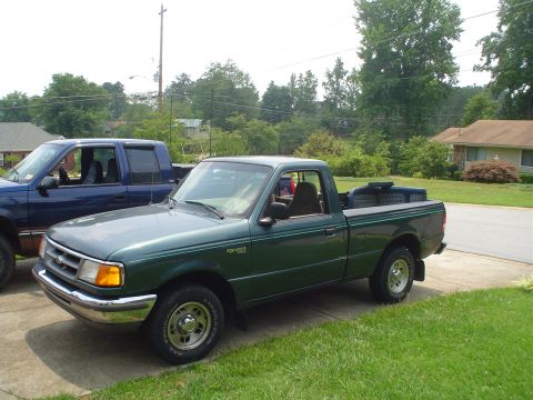 1981 Ford Bronco - A green Ford Ranger pickup truck is parked in a driveway next to another truck.
