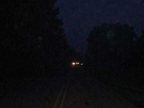 1981 Ford Bronco - Headlights of two vehicles are visible on a dark road at night.