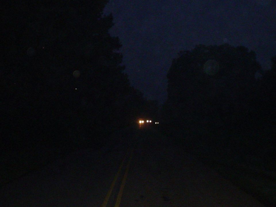 Two vehicles with headlights on driving on a dark road at night