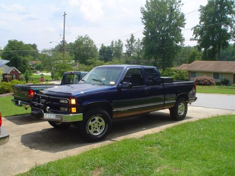 1981 Ford Bronco - A dark blue pickup truck is parked on a driveway, with another truck visible behind it.