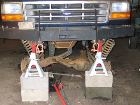 1995 Ford Bronco - Front suspension of a blue 1992 Ford Bronco is elevated on jack stands for maintenance.