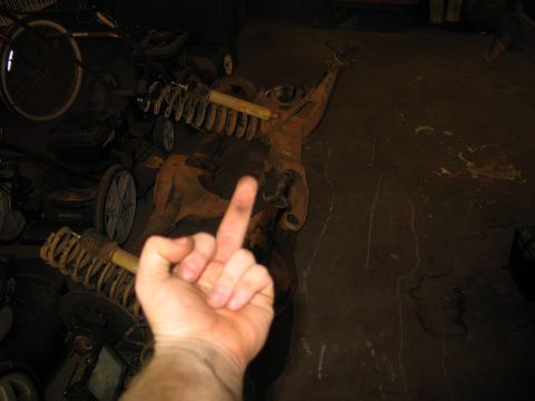 1995 Ford Bronco - A hand gives the middle finger in front of old vehicle parts and lawn equipment.