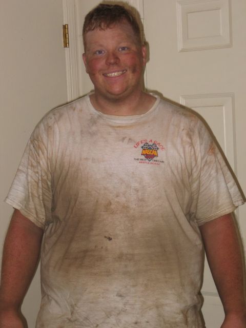 1995 Ford Bronco - A man smiles while wearing a dirty t-shirt with a NASCAR logo, appearing to have been working outdoors.