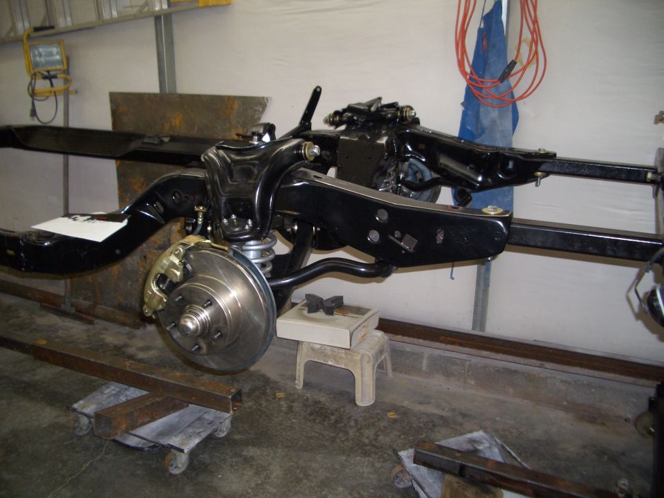Restored gloss-black car frame on stands with new front control arms, coil spring and disc brake