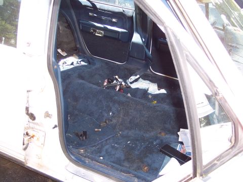 2001 Ford Crown Victoria - The interior of a car shows exposed wiring and a disassembled door panel, indicating disrepair.