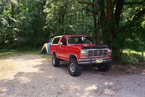 1986 Ford Bronco - Red 1986 Ford Bronco parked at a campsite with a tent.