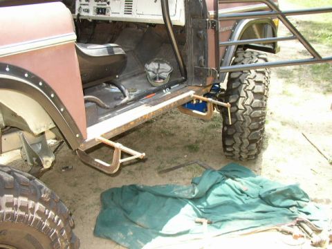 1995 Ford Bronco - Modified Ford Bronco with off-road tires and roll cage, undergoing work.