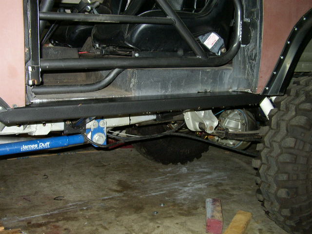 Off-road vehicle interior with roll cage, racing seats, and modified suspension components including a blue James Duff shock absorber