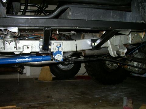 1995 Ford Bronco - The underside of a vehicle shows suspension components and a blue shock absorber.