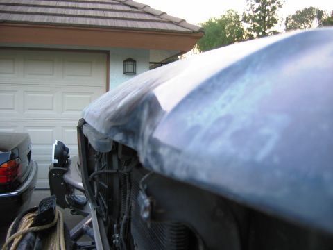 1985 Ford Bronco - Close-up of a damaged blue Ford Bronco hood with primer, revealing the grille and front end.