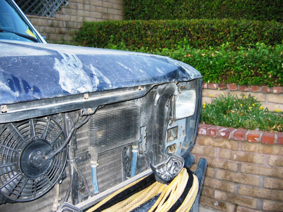 Front corner of blue Ford SUV with grille off exposing electric fan and radiator