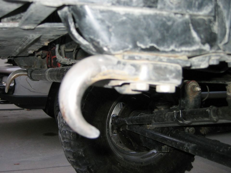 Underside of vehicle showing axle, tow hook, leaf spring and tire