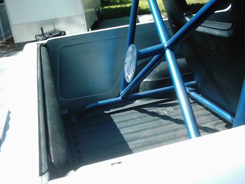 1978 Ford Bronco - Roll cage installed in the bed of a white pickup truck.