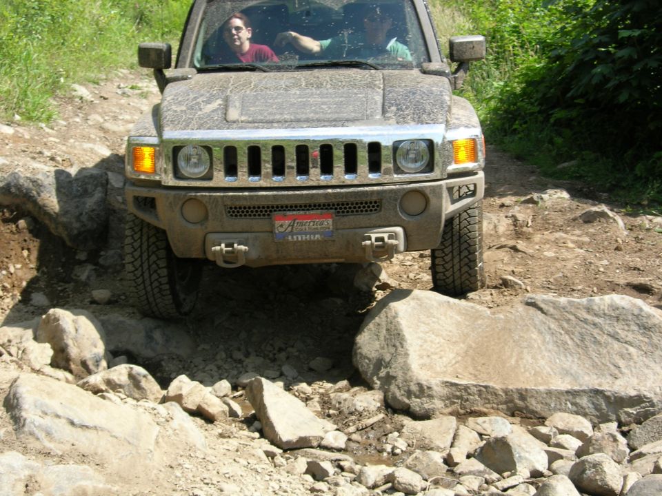 Hummer H3 crawling over large rocks on a trail with two people inside