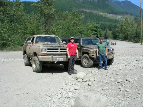 1989 Dodge Power Ram - Two men stand with a lifted 1989 Dodge Ramcharger SUV and a Hummer H3 in a gravel lot with a mountainous backdrop.