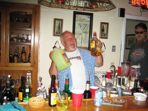 1968 Ford Mustang - A man enthusiastically presents drinks at a well-stocked home bar, with another person visible in the background.