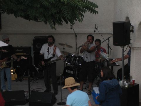 1968 Ford Mustang - A band plays music at an outdoor event, with musicians on guitars, drums, and trumpet.