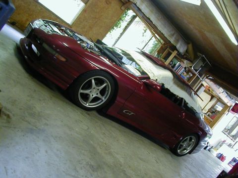 1994 Ford Probe - A maroon coupe with a GT badge is parked inside a garage, its hood open.