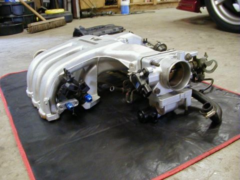 1994 Ford Probe - Intake manifold assembly removed from a vehicle, resting on a black mat.