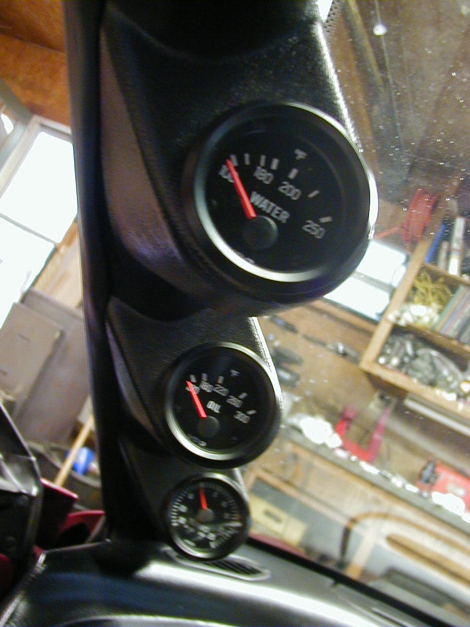 Car interior with water and oil gauges mounted on the dash. A third smaller gauge is below them