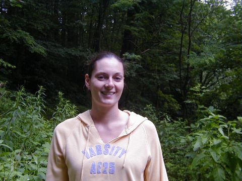 1994 Ford Probe - A woman smiles while standing in a wooded area, wearing a yellow hoodie with "VARSITY AE25" printed on it.