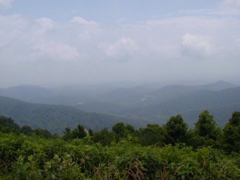 1994 Ford Probe - A scenic view of rolling mountains under a hazy sky, with lush green foliage in the foreground.