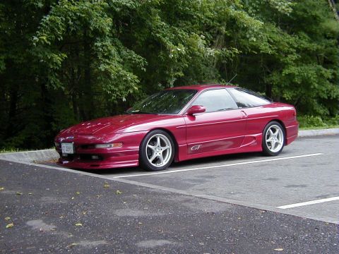 1994 Ford Probe - A red 1994 Ford Probe GT is parked in a lot with trees in the background.