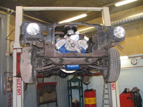 1972 Ford Mustang - The front end of a car is removed while it's elevated on a lift, revealing the engine and chassis.
