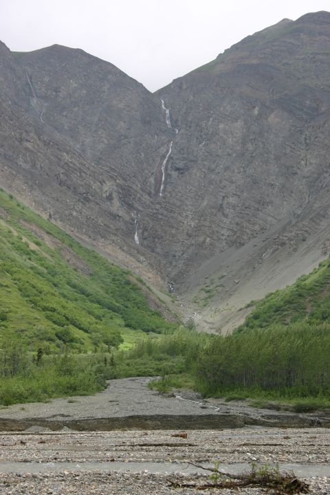 2003 Jeep TJ - A scenic mountain valley features waterfalls and lush green slopes under an overcast sky.
