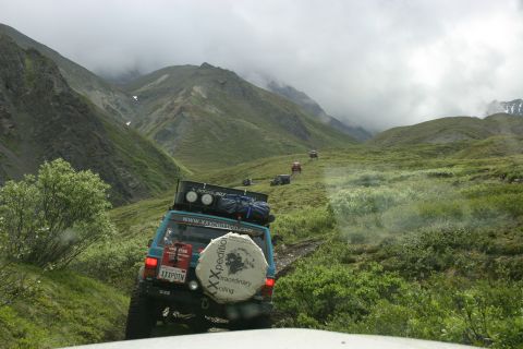 2003 Jeep TJ - A convoy of off-road vehicles navigates a mountain landscape under cloudy skies.