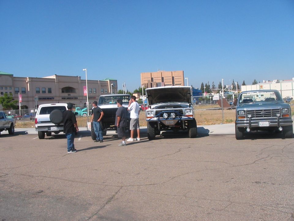 Silver Ford Bronco with aftermarket bumper and lights, hood open, parked in a lot