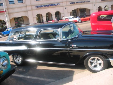 1986 Ford Bronco - A black 1957 Chevrolet Nomad station wagon is parked next to other vehicles.