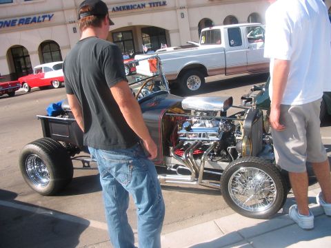 1986 Ford Bronco - A custom hot rod with a powerful engine is on display, with onlookers and other vehicles nearby.