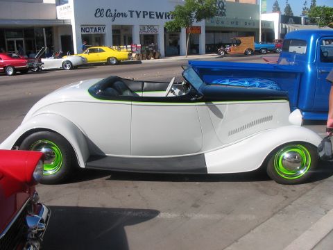 1986 Ford Bronco - A custom hot rod with bright green wheels is parked on a street next to other vehicles.