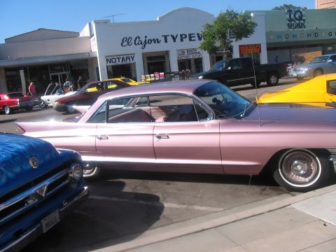 1986 Ford Bronco - A classic pink Cadillac coupe parked on a street with other vehicles and buildings in the background.