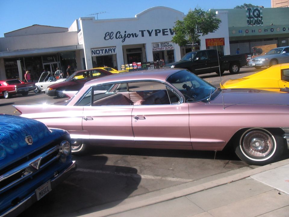 Pink Cadillac coupe, side view, with chrome trim and whitewall tires. Interior visible
